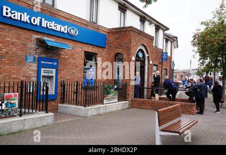 Le persone fanno la fila per entrare in una filiale della Bank of Ireland nel villaggio di Finglas, Dublino. Bank of Ireland si è scusata dopo che un errore ha portato alcuni dei suoi clienti a prelevare o trasferire più denaro di quanto non fosse nei loro conti. La banca ha detto che si trattava di un problema tecnico con i suoi servizi e non di un attacco informatico. Data foto: Mercoledì 16 agosto 2023. Foto Stock