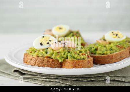 Fette di pane con guacamole saporito, uova e gamberi sul tavolo, primo piano Foto Stock