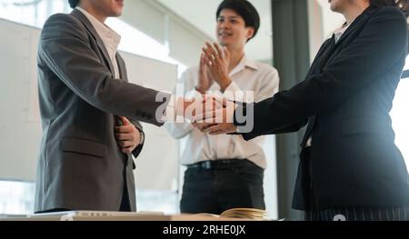 Partner commerciali asiatici stretta di mano di successo insieme di fronte al lavoro di squadra di gruppo affari che battono le mani vincendo il successo concordano in ufficio Foto Stock