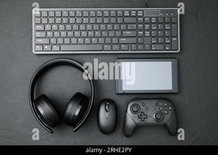 Dispositivi neri: Gamepad, mouse per computer, tastiera, cuffie e tablet pc. Primo piano del concetto di gioco su sfondo nero Foto Stock