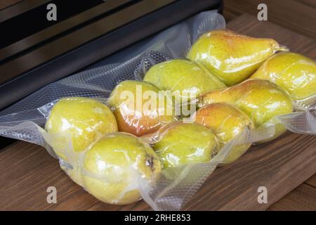 Confezionamento di pere fresche con un confezionatore sottovuoto per la conservazione a lungo termine. Foto Stock