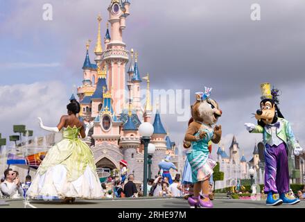 Disneyland Paris; personaggi Disney di fronte al castello di Disneyland che ballano durante la parata di Disneyland; Principessa Tiana, Clarice e Pippo; Francia Foto Stock