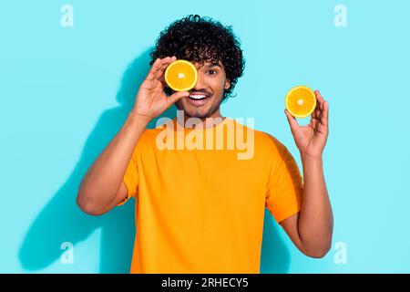 Ritratto fotografico di giovane eccitato ragazzo funky promozione frutta d'arancia fresca sano coperchio vitamine occhio isolato su sfondo di colore acquamarina Foto Stock