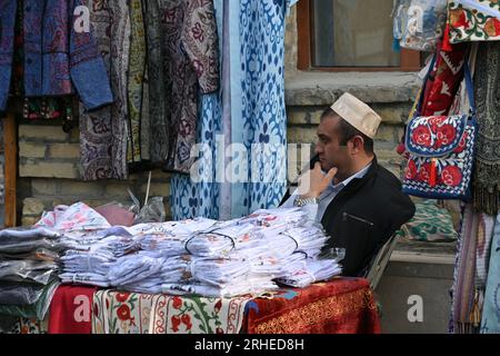 Venditore di vestiti nella sua stalla all'interno della città vecchia di Bukhara, Uzbekistan Foto Stock