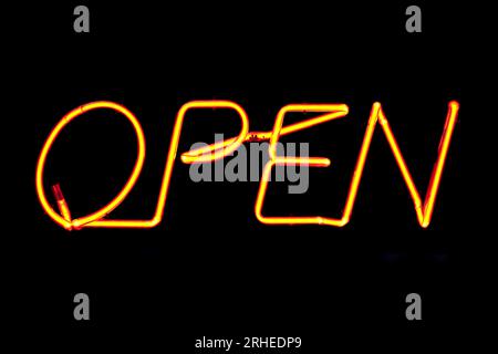 Un cartello al neon arancione all'interno della finestra di un pub irlandese con scritto "Open". Foto Stock