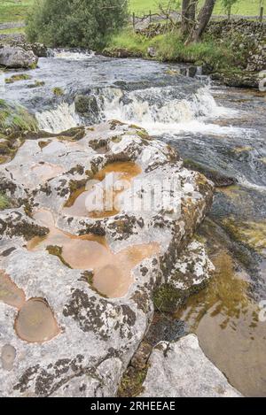 Scavato nella pietra nel letto del fiume Skirfare (vicino a una mini-cascata) a Littondale, North Yorkshire, Yorkshire Dales National Park, agosto 2023. Foto Stock