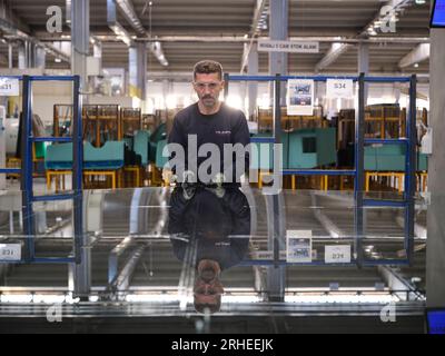 Fabbrica per la produzione di finestrini e parabrezza per auto. Lavoratore manuale che assembla finestre in PVC e finestrini per auto. Lavoratori che confezionano fogli di vetro in magazzino Foto Stock