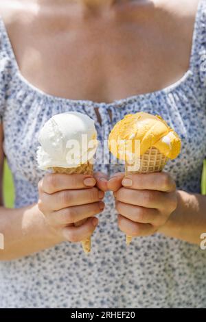 Le mani delle donne tengono un gelato rinfrescante in coni di waffle con un pizzico di saporito sapore di limone Foto Stock
