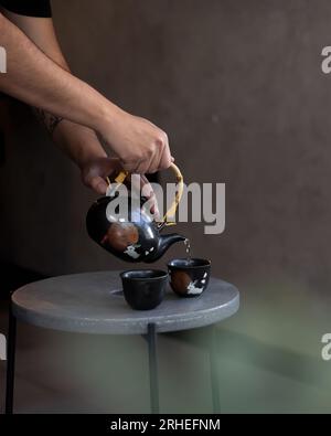 serve te' con una speciale teiera in ceramica su due piccole tazze di te', su un tavolo di cemento, messico america latina Foto Stock