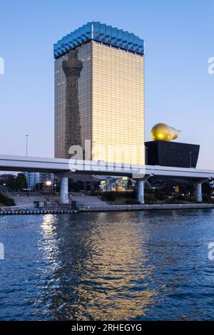 Vista della Asahi Beer Hall (alias Super Dry Hall, o Flamme d'Or) con il Tokyo Skytree riflesso sul lato, visto da Asakusa, attraverso la Sumida Foto Stock