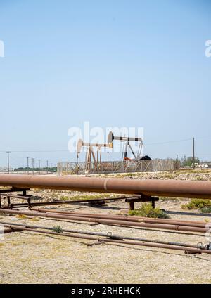 Infrastrutture per giacimenti petroliferi del Bahrein - tubi petroliferi, martinetto per pompe, cavalcaia petrolifera, pompa per travi che estrae petrolio greggio da pozzi petroliferi nel deserto del Bahrein Foto Stock