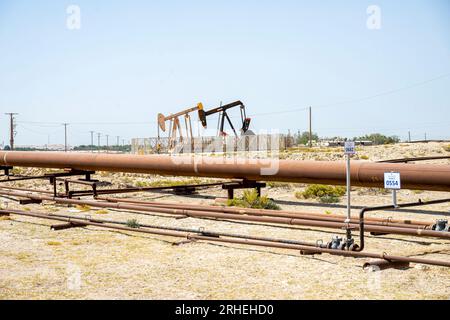 Infrastrutture per giacimenti petroliferi del Bahrein - tubi petroliferi, martinetto per pompe, cavalcaia petrolifera, pompa per travi che estrae petrolio greggio da pozzi petroliferi nel deserto del Bahrein Foto Stock