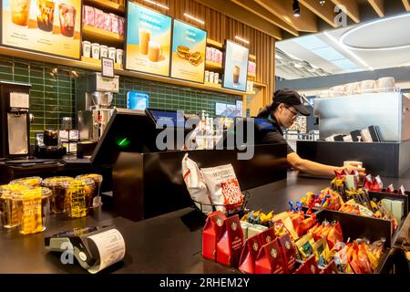 McDonalds Bahrain Airport Cafe - impiegato che consegna caffè McDonalds dietro il bancone Foto Stock