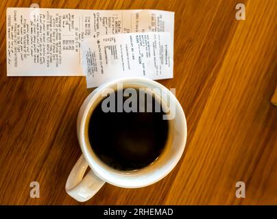 Tazza di caffè nel caffè dell'aeroporto McDonalds Bahrain, una ricevuta accanto alla tazza di caffè, vista dall'alto sul tavolo Foto Stock