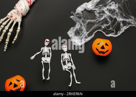 Composizione con scheletri, mano, ragnatela e zucche per festeggiare Halloween su sfondo scuro Foto Stock