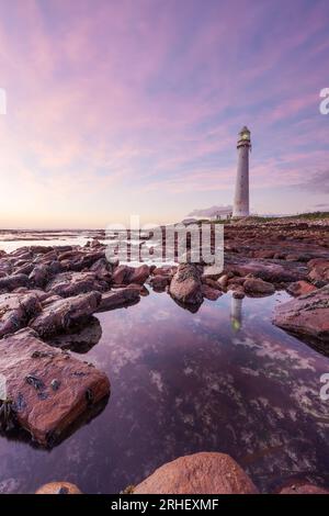 Fotografia del paesaggio oceanico del faro di Slangkop dell'oceano Atlantico a Kommetjie, in Sudafrica, con nuvole rosa al tramonto per i turisti in viaggio Foto Stock