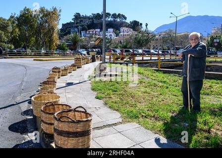 Uomo che vende cestini in vimini tessuti tradizionali per strada al mercato nel vecchio quartiere di Kalamata, Messinina, Poloponnese, Grecia. Foto Stock