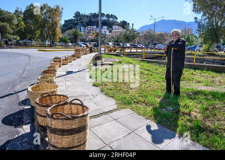 Uomo che vende cestini in vimini tessuti tradizionali per strada al mercato nel vecchio quartiere di Kalamata, Messinina, Poloponnese, Grecia. Foto Stock