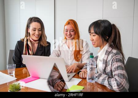 Tre donne d'affari che lavorano a progetti in ufficio, ambiente multietnico e colleghi felici Foto Stock