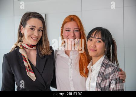 Tre giovani donne d'affari che sorridono insieme in ufficio, gruppo multietnico Foto Stock