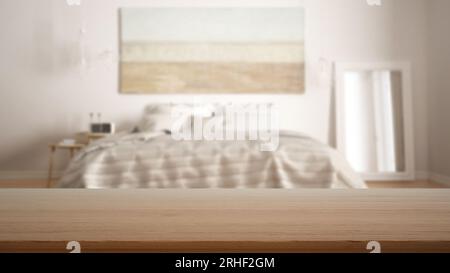 Tavolo vuoto in legno, scrivania o ripiano con vista sfocata della camera da letto bianca scandinava, letto con cuscini, specchio e tavolino, arredamento moderno Foto Stock