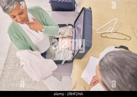 Coppia matura, vestiti e valigia per il trasporto a casa, in vacanza o in vacanza con vista dall'alto. Uomo, donna e preparate i bagagli in casa, pensando e.. Foto Stock