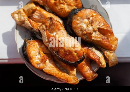 Le bistecche di salmone alla griglia si trovano su un piatto e sul tavolo c'è una bella luce del sole. Pasto delizioso e salutare Foto Stock