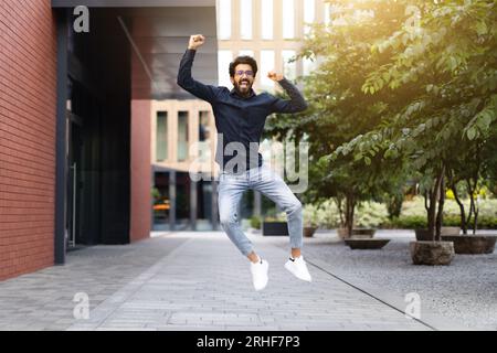Un giovane uomo dell'est entusiasta che festeggia il successo, saltando per strada Foto Stock