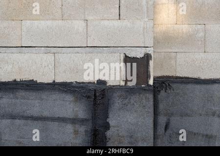 Materiale per tetti bituminosi, rivestimenti impermeabili applicati sulla parete inferiore di una nuova casa in costruzione Foto Stock