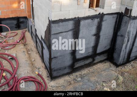 Materiale per tetti bituminosi, rivestimenti impermeabili applicati sulla parete inferiore di una nuova casa in costruzione Foto Stock