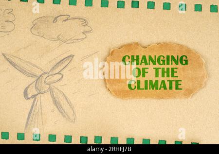 Un generatore eolico e le nuvole sono disegnate su cartone con fori verdi, accanto ad esso si trova un cartone con l'iscrizione - cambiamento del clima. Ecolo Foto Stock