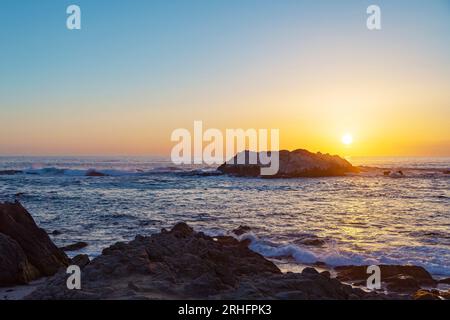 Gli uccelli si siedono su una roccia durante il tramonto sul mare. Tramonto in California con sagome di rocce e gabbiano marino in lontananza. Uccello silhouette con tramonto e mare. I gabbiani si siedono su una roccia al tramonto Foto Stock