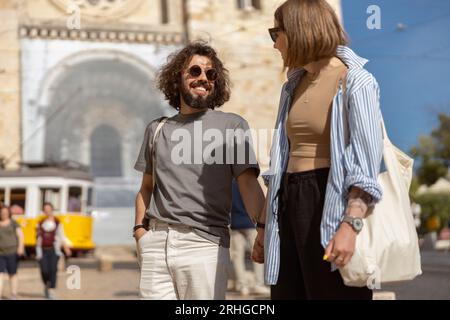 Coppia di viaggiatori sorridenti che camminano sullo sfondo della vecchia strada della città e si tengono per mano Foto Stock