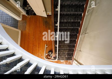 Una vista dall'alto verso il basso di una vecchia scala di legno all'interno di una casa abbandonata. Foto Stock
