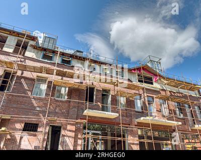 edificio in mattoni in ristrutturazione circondato da impalcature. restauro della facciata. Foto Stock