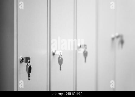Primo piano dei tipici armadietti in metallo grigio con le chiavi nelle porte Foto Stock