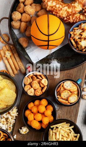 Set di vari tifosi di pallacanestro e spuntini, patatine, salse su sfondo bianco. Bottiglie di birra e accessori per ventole. Vista dall'alto. Foto Stock