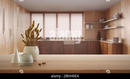 Tavolo in legno, scrivania o mensola da vicino con vasi in ceramica e vetro con piante secche, cannucce su una vista sfocata della cucina in legno di japandi in stile minimalista Foto Stock