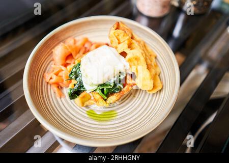 Cialde di patate, uova in camicia, crema di avocado con salmone e uova. Colazione sana, proteine. Piatto del ristorante. Foto Stock