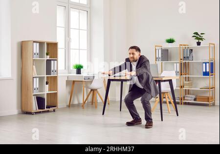 Uomo d'affari in costume che fa esercizi fisici durante una pausa al lavoro in ufficio Foto Stock