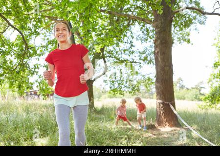 Madre felice che corre con figlio e figlia mentre gioca in giardino Foto Stock