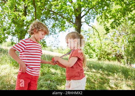 Sorella che mostra la medaglia al fratello mentre si trova in giardino durante il giorno di sole Foto Stock