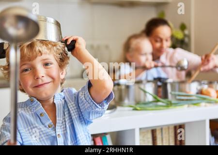 Ritratto di un ragazzo sorridente che gioca con i vasi in cucina a casa Foto Stock