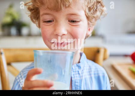 Sorridente biondo che tiene un bicchiere di latte a casa Foto Stock