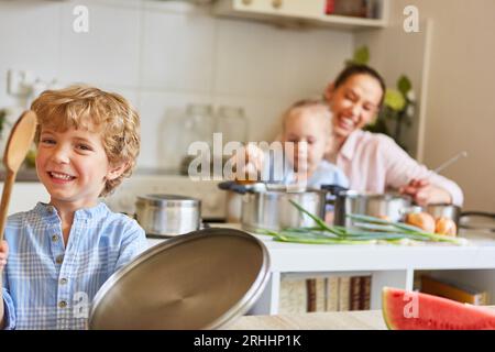 Ritratto di un ragazzo sorridente che si diverte con la famiglia in cucina a casa Foto Stock