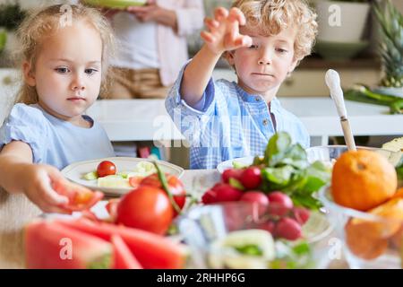 Fratello e sorella preparano insalata di verdure in cucina a casa Foto Stock