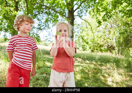 Ritratto di una ragazza sorridente che mostra la medaglia mentre si trova in piedi con il fratello in giardino Foto Stock