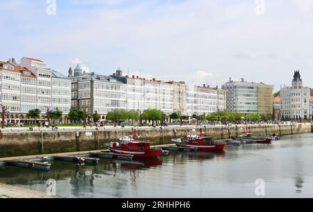 Barche da pesca ormeggiate nel porto con edifici lungo Avenida Marina A Coruña Galizia Spagna Foto Stock