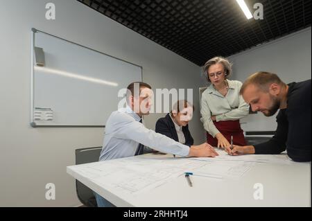 L'estrusione femminile valuta il lavoro dei subordinati. Progettisti ingegneri a una riunione. Foto Stock