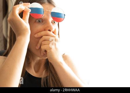 Bandiera della Russia sugli occhiali di una ragazza, cieca e ingannata dalla propaganda russa, non vede nulla a causa della propaganda Foto Stock